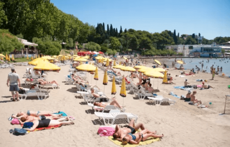 Sandy beach Bačvice with sunbeds. People are sunbathing on the beach.