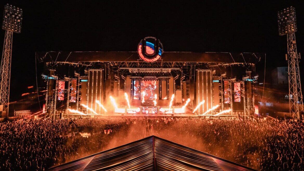 A large crowd of people standing in front of a stage at a concert.